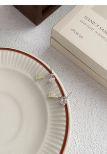 Detail of S925 silver star drop earrings with yellow zircon crystals on a ceramic plate