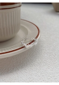 Detail of S925 sterling silver star ring resting on a white ceramic coffee cup rim