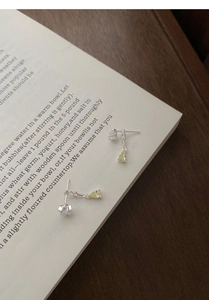 Macro detail of S925 silver star drop earrings with yellow zircon on an open book