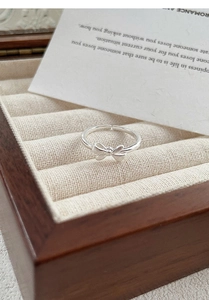 Detailed view of silver bow-shaped open ring on a premium jewelry display box