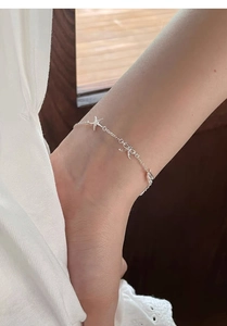 Detail of S999 sterling silver anklet with starfish and bow pendants on an ankle