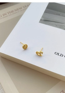 Macro view of gold S925 silver asymmetric rocking horse and coin stud earrings