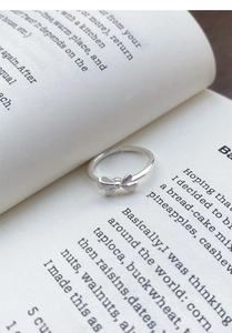 Macro detail of silver bow ring with brushed finish and polished band on book page