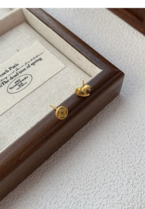 Detail of S925 silver asymmetric matte gold studs featuring a coin and rocking horse