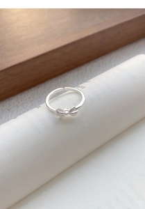 Close-up of S999 sterling silver bow ring with brushed metal texture and open band design