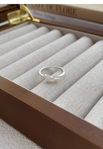 Macro detail of a brushed silver bow ring on a velvet cushion inside a jewelry box