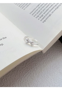 Detail of S999 sterling silver bow ring featuring matte bow and polished band finish