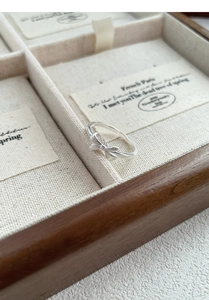 Detailed side view of silver bow ring with matte finish in a vintage wooden jewelry box