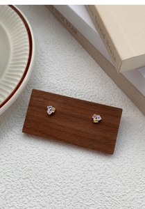Détail de boucles d'oreilles en argent S999 avec zircons colorés sur support en bois