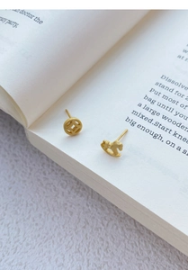 Detail showing matte gold S925 silver stud earrings with coin and rocking horse shape