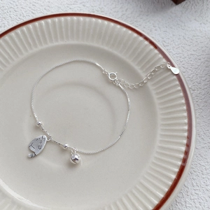 Bracelet S925 en argent fin avec pendentif chat et clochette sur plat céramique