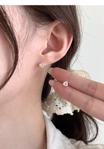 Détail de boucles d'oreilles puces en zircone colorée portées avec une base en argent