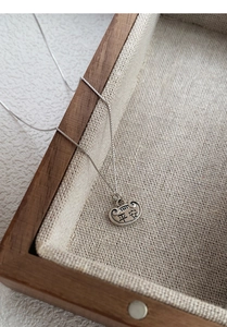 Macro shot of S925 sterling silver Ruyi lock necklace with Ping An engraving on wood