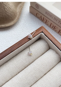 Détail macro de boucles d'oreilles en argent S999 avec zircons carrés colorés sur bois