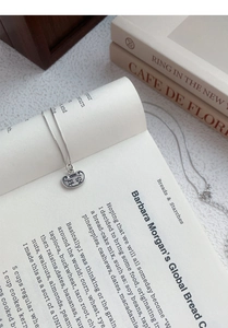 Close-up of S925 silver Ping An lock necklace with Chinese engraving on a book