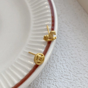 Asymmetric S925 silver matte gold stud earrings with horse and coin shapes on ceramic tray