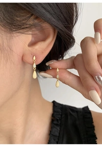 Detailed view of elegant gold-tone S999 silver drop earrings with zircons on model