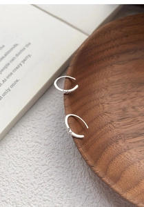 Detail of S925 sterling silver C-shaped hoop earrings with zircon pavé and heart charm