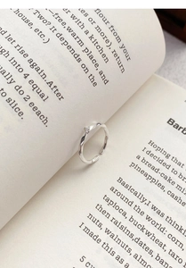 Macro detail of a silver Mobius twist ring with zircon, nestled in an open book page