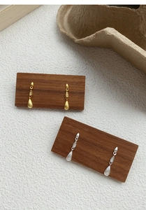 Detailed macro view of brushed silver and gold teardrop earrings with zircon accents