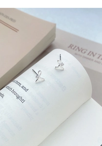 Detail shot of silver ribbon stud earrings with sparkling cubic zirconia on book pages
