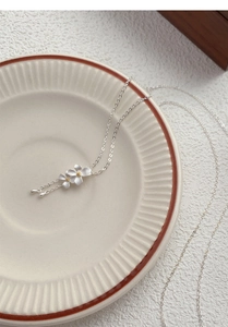Dettaglio macro del ciondolo gardenia in argento S999 con stami dorati su ceramica