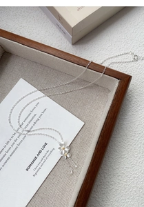 Dettaglio della collana in argento S999 con fiori di gardenia e nappe su vassoio