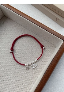 Detail of red braided S925 silver bracelet with money coin and horse charm