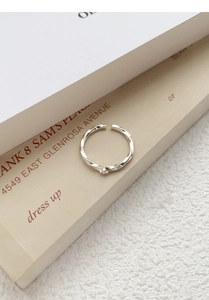 Close-up of S999 silver Mobius ring with zircon detail on a minimalist book background