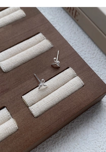 Detailed close-up of S999 silver bow earrings with zircon on a wooden jewelry display