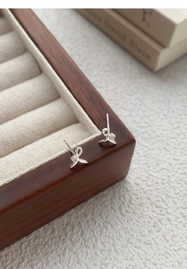 Close-up of S999 sterling silver bow earrings with zircon on premium wooden jewelry box