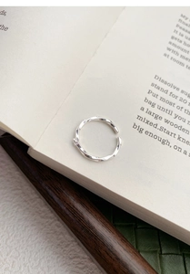Detail view of Mobius S999 silver ring with zircon on an open book background
