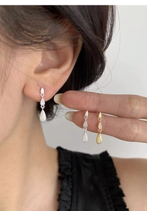Detailed macro view of S999 sterling silver teardrop earrings with brushed metal texture