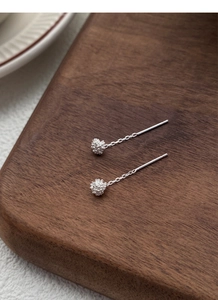 Macro detail of S925 sterling silver dandelion tassel earring on a wooden background