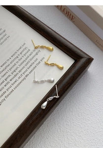 Macro detail of brushed teardrop earrings in gold and silver finish with zircon studs