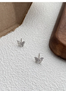 Macro detail of S999 silver butterfly stud earrings with hollow wings and cubic zirconia