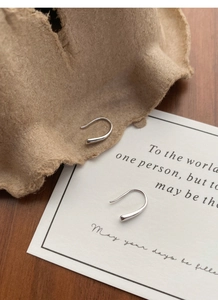 Artistic close-up of S999 sterling silver teardrop hook earrings on a minimalist background
