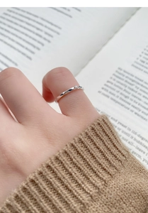 Detailed view of silver Mobius ring with zircon worn while reading a book