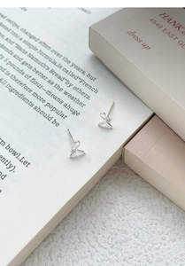 Close-up of S999 sterling silver bow earrings with tiny zircon inlay on a book page