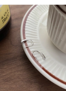 Close-up of S925 sterling silver stamp on minimalist teardrop earrings over ceramic