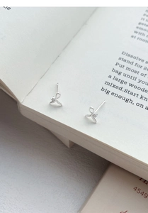 Close-up of elegant silver bow earrings with zircon stones on an open book page