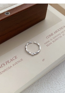 Detailed shot of silver Mobius ring with twisted texture and zircon on a book base