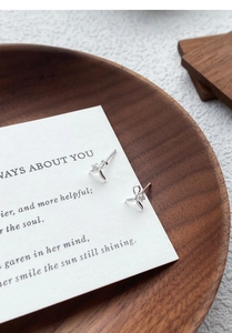 Macro detail of silver bow earrings with center diamond on an elegant card display
