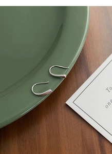 Detailed close-up of S999 sterling silver teardrop earrings on a vintage green ceramic tray