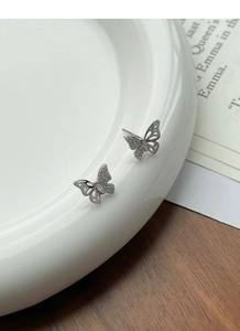 Macro shot of silver butterfly stud earrings with sparkling zircon inlay and hollow texture