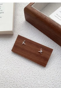 Detailed close-up of a silver fishtail stud earring with a central sparkling zircon inlay