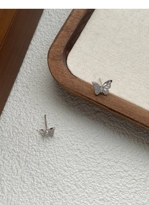 Detail view of butterfly silver earrings featuring asymmetric zircons and hollow design