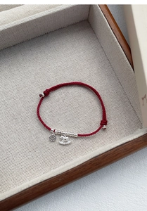 Detail of red braided silk bracelet with S925 silver coin and crystal horse charms