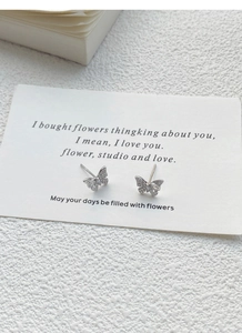 Detail of silver butterfly studs with hollow wings and sparkling micro-inlaid stones