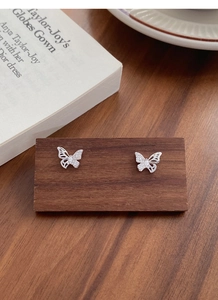 Macro shot of silver butterfly stud earrings with hollow design and cubic zirconia stones